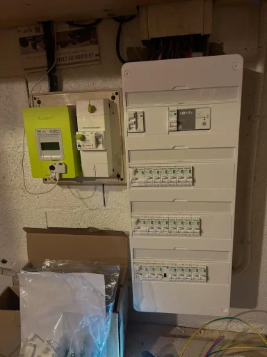 tableau électrique résidentiel fermé et propre, avec son capot blanc, situé à côté d'un compteur Linky vert.