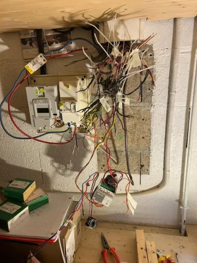 Tableau électrique en plein chantier à Antony (92) de câblage, avec de nombreux fils électriques désordonnés qui pendent du mur.