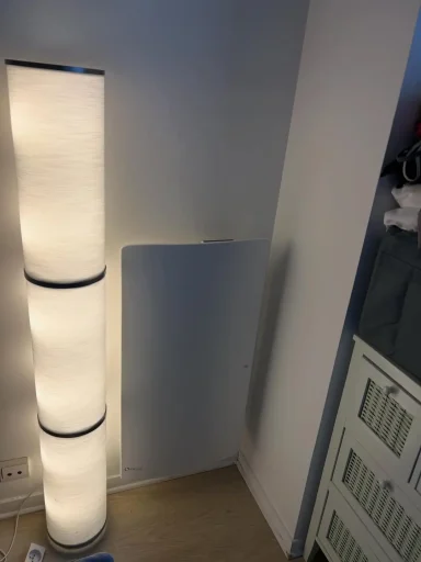 Radiateur électrique mural de format vertical, au design épuré et blanc, installé dans un angle ou sur un pan de mur étroit.